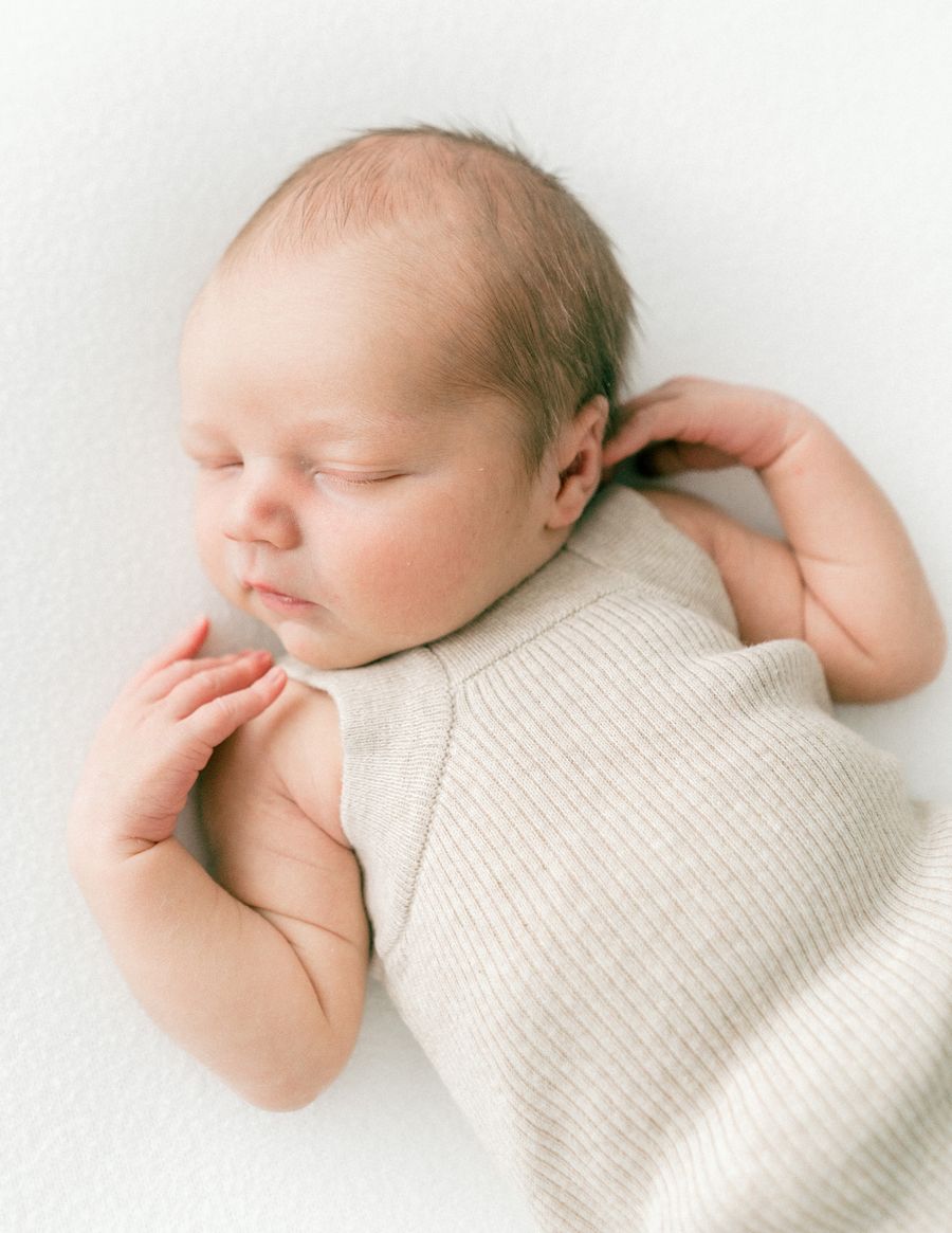 Sleeping newborn in a cream knit romper