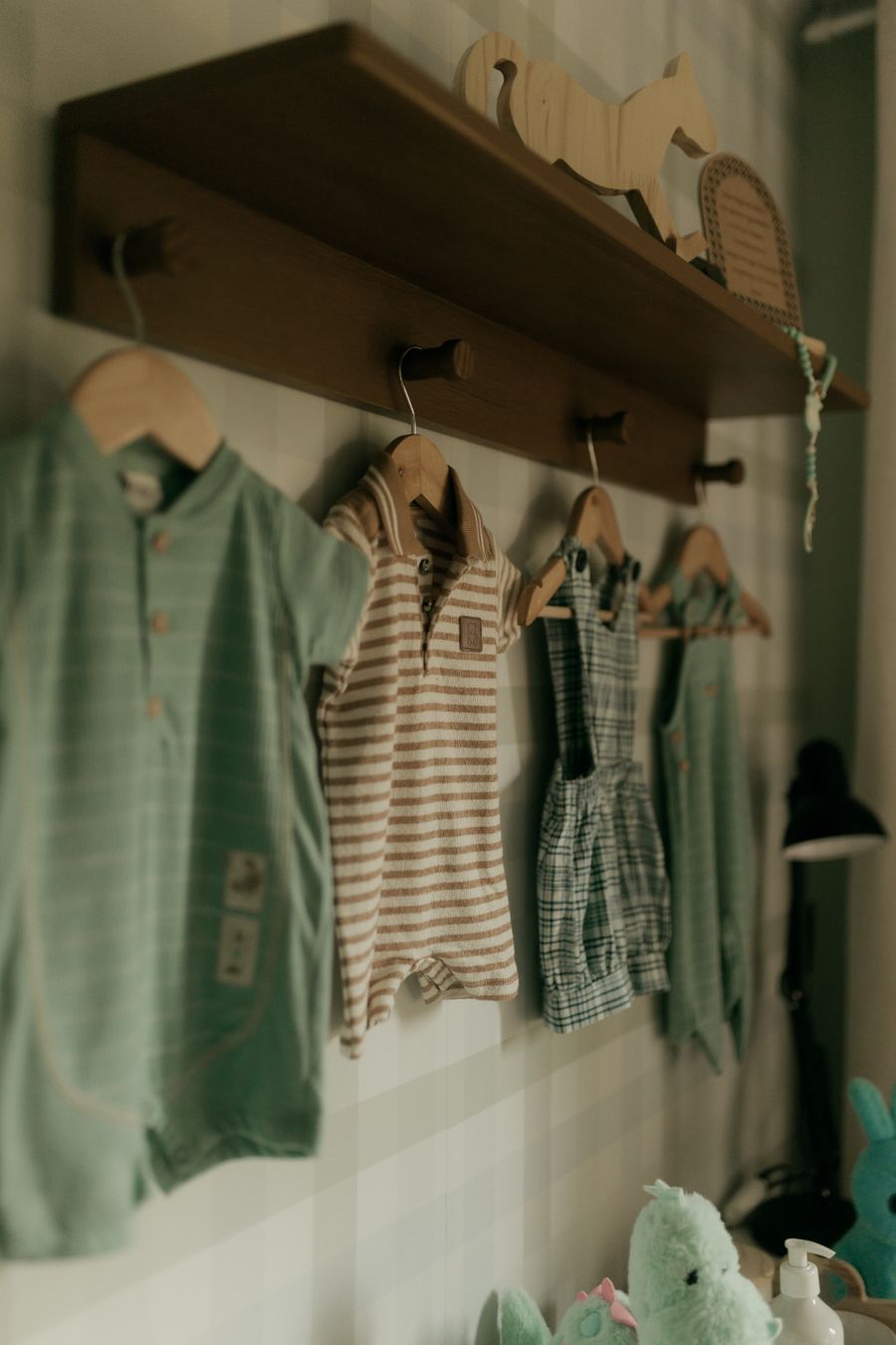 Sage and striped baby rompers hanging on hooks